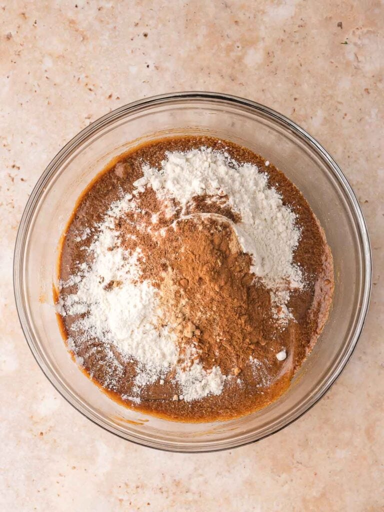 Bowl with flour, cinnamon, and ginger added to the wet ingredients for Gingerbread Man Cookies.