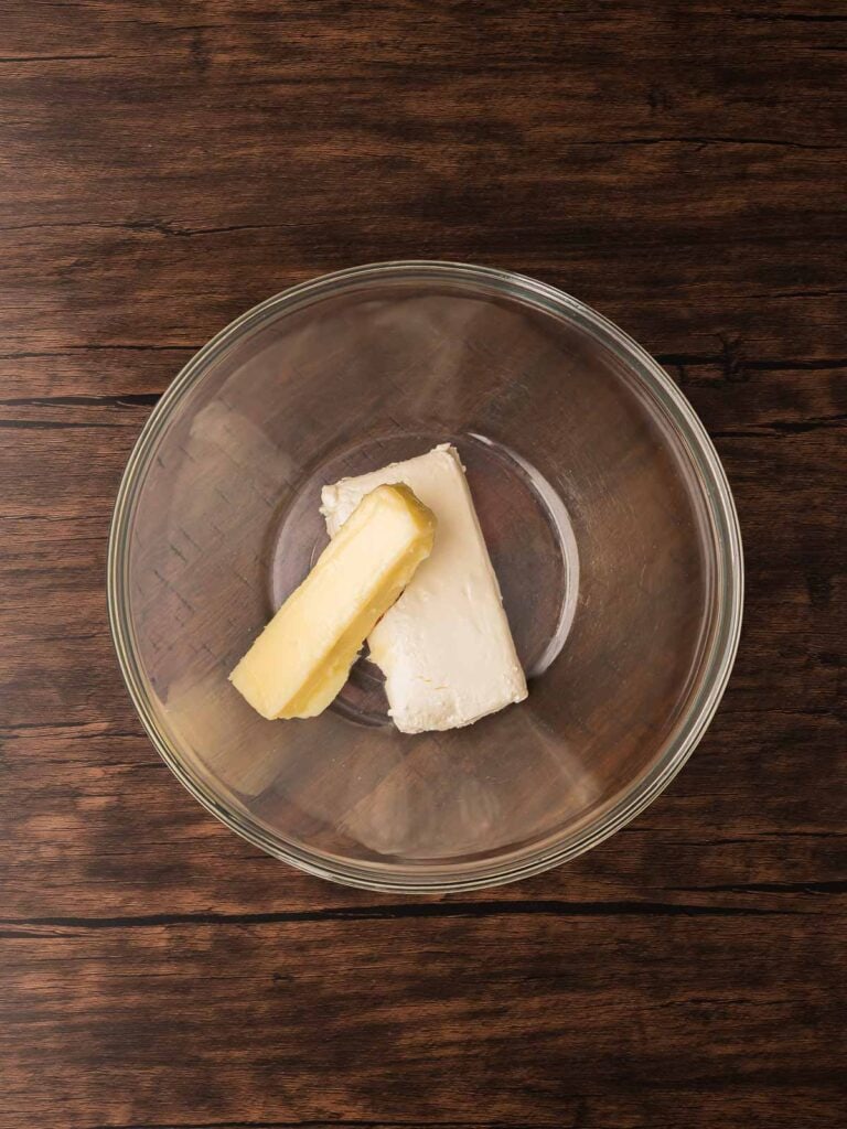 Softened butter and cream cheese in a glass mixing bowl ready to make Coconut Snowball Cookies.