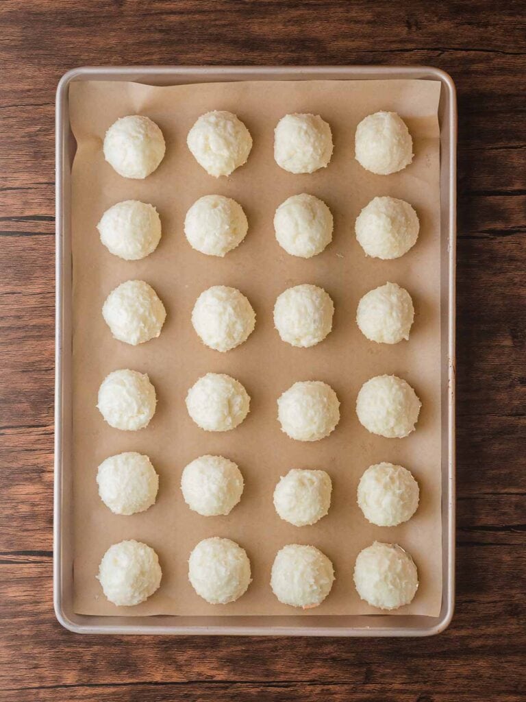 Rolled Coconut Snowball Cookies arranged on a parchment-lined baking sheet before chilling.