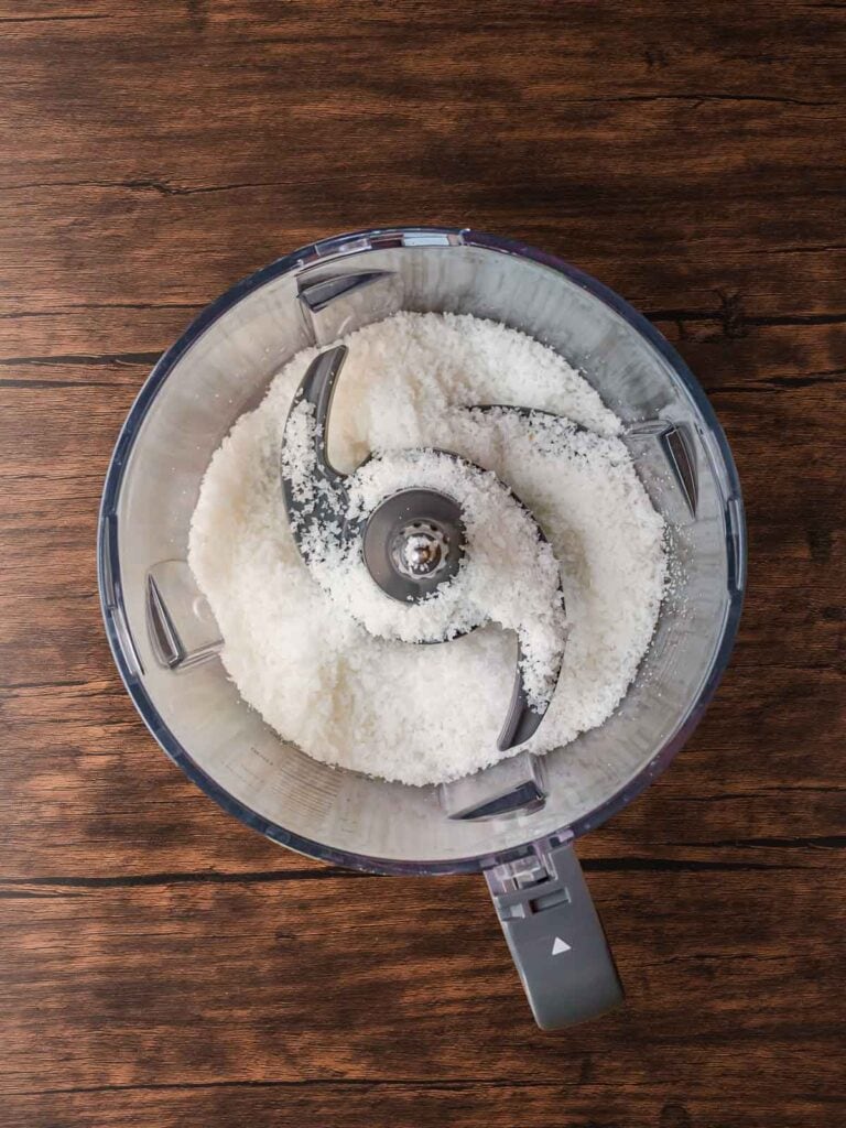 Shredded coconut pulsed in a food processor to create fine flakes for coating Coconut Snowball Cookies.