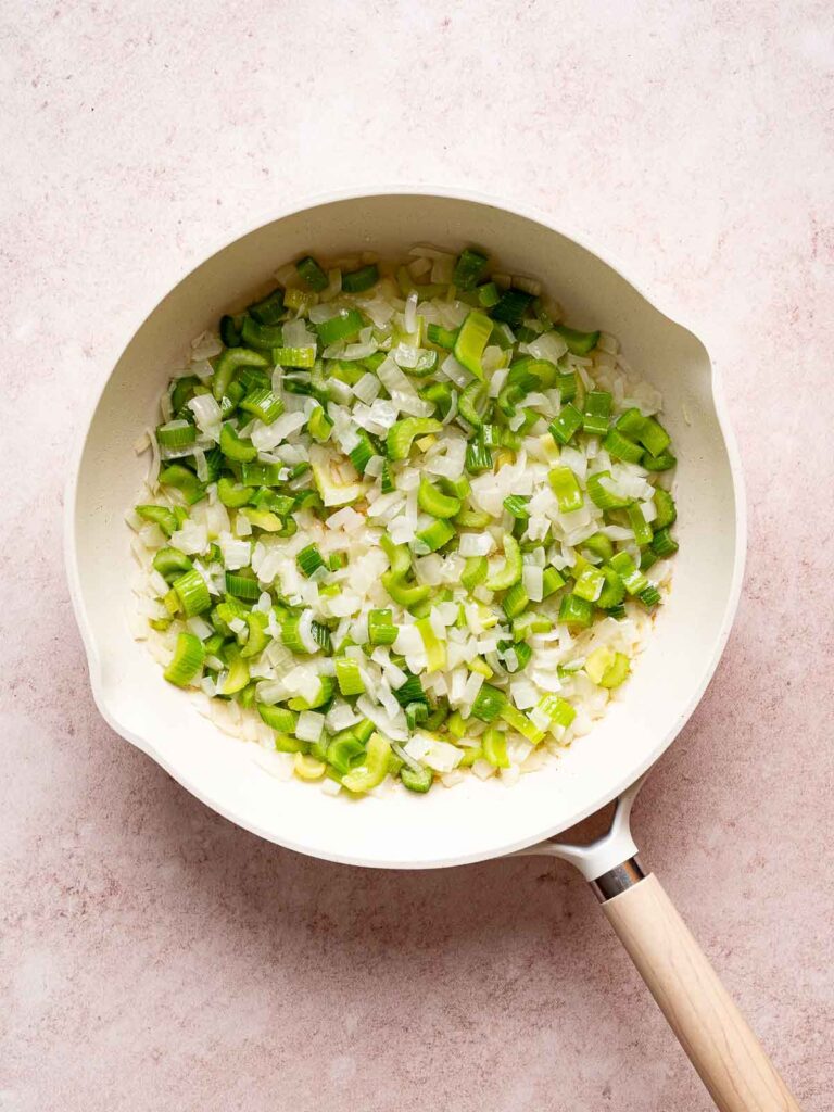 Onions and celery sautéing in a skillet with butter for the base of sourdough stuffing.