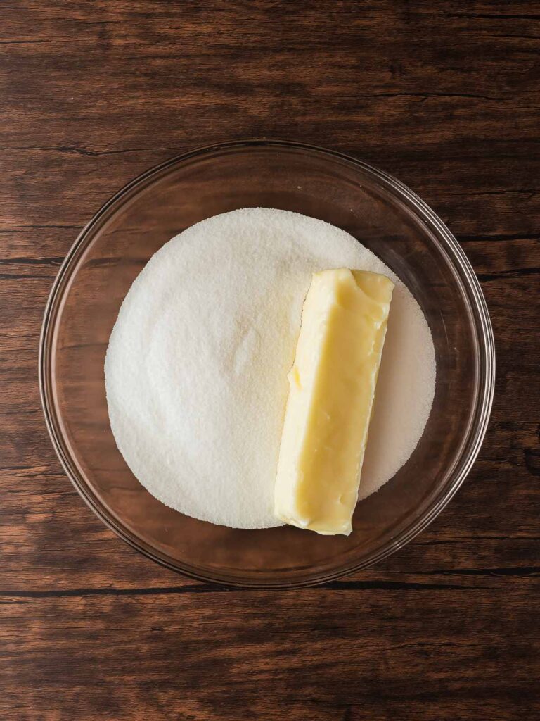 Mixing softened butter and sugar in a glass bowl for Turtle Thumbprint Cookies.