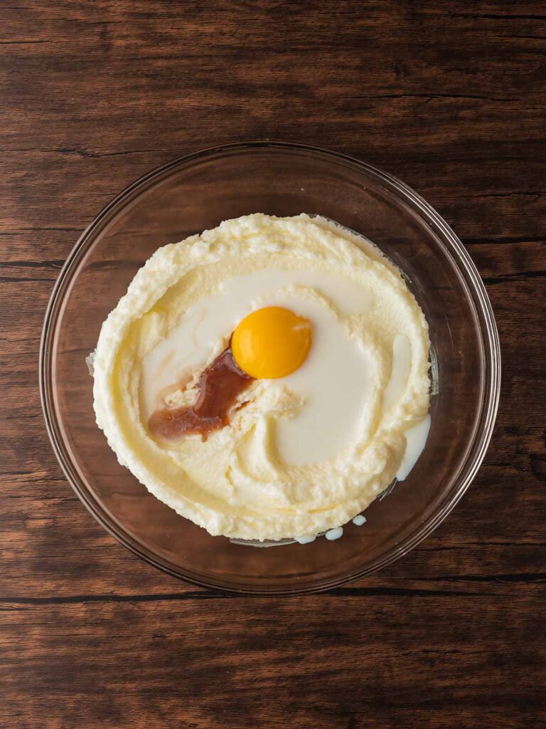 Creamed butter and sugar with egg yolk, milk, and vanilla in a mixing bowl.
