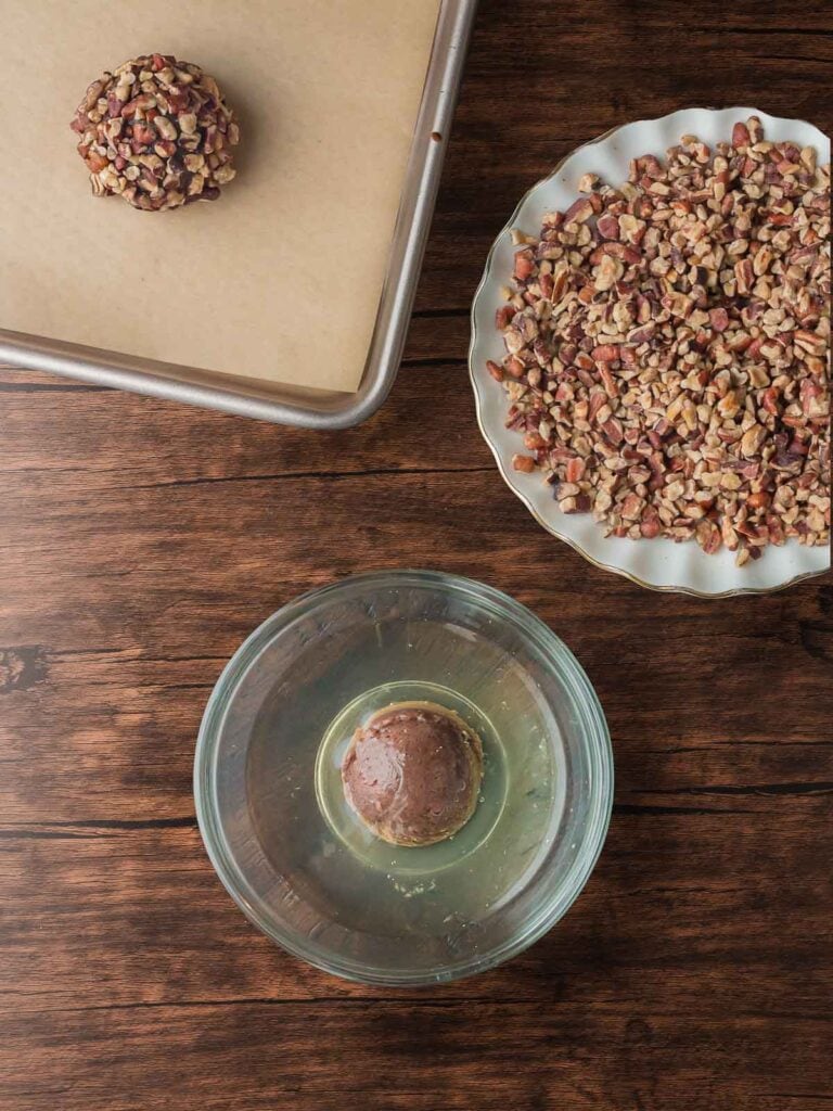 Rolling cookie dough balls in egg white and finely chopped pecans.