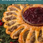 Side view of flaky sausage roll wreath sections with sesame seeds next to a bowl of cranberry sauce by Tessie's Table.