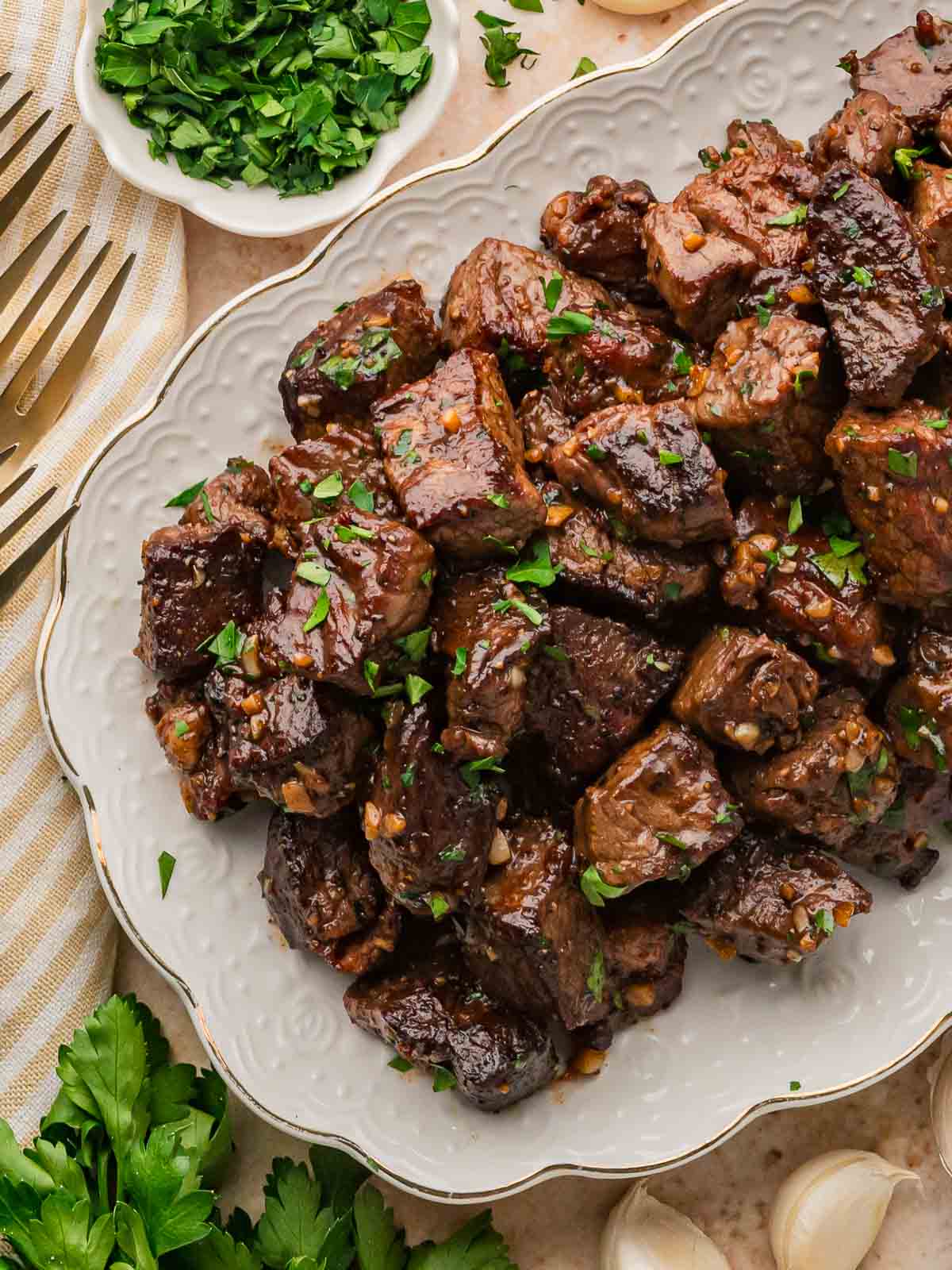 Platter of garlic butter steak bites sprinkled with chopped parsley.