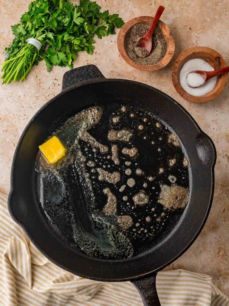 Melted butter bubbling in a cast iron skillet, ready for cooking garlic butter steak bites.