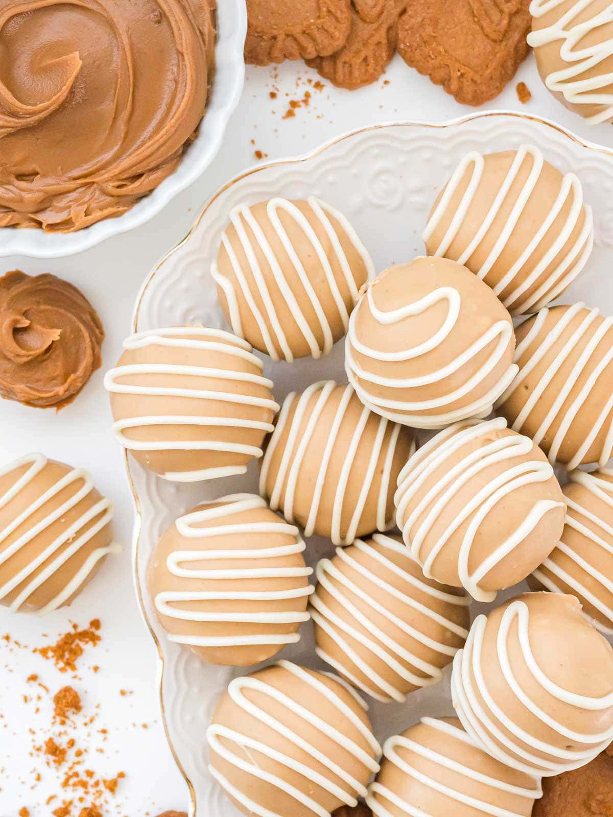 Plate of no-bake Biscoff truffles with cookie butter, Biscoff cookies, and crumbs scattered around for texture.