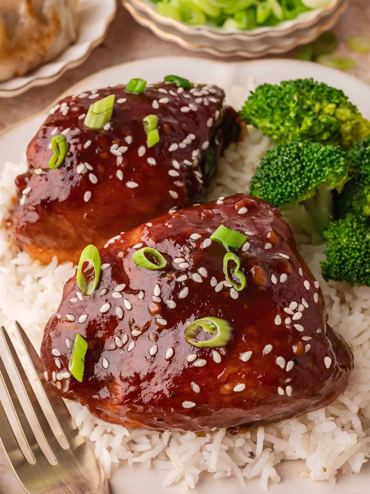 Plate of Crock Pot honey garlic chicken served over fluffy white rice with steamed broccoli and sesame seed garnish.