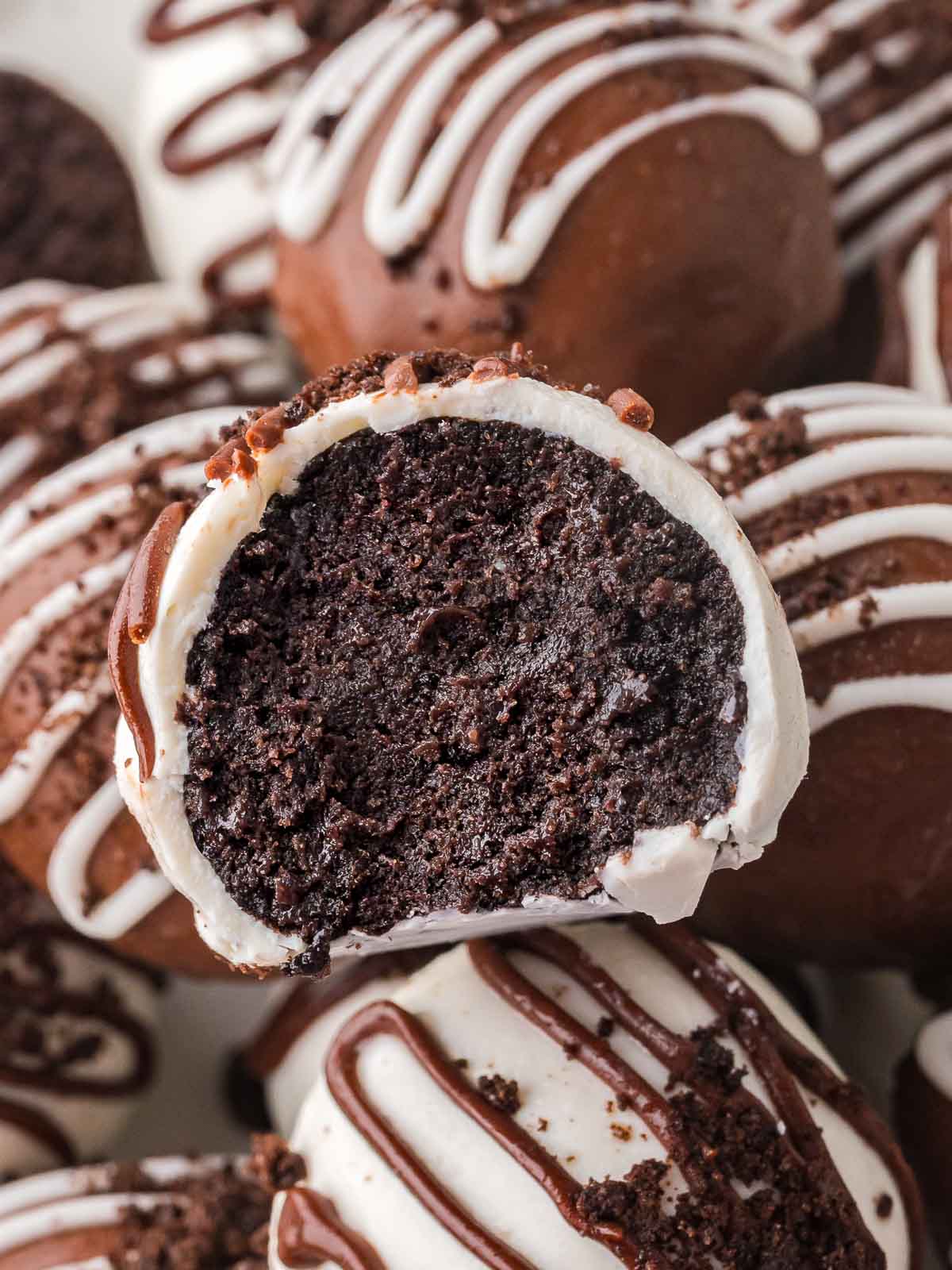 A bitten Oreo truffle showing the soft chocolate cookie filling inside the white chocolate coating.
