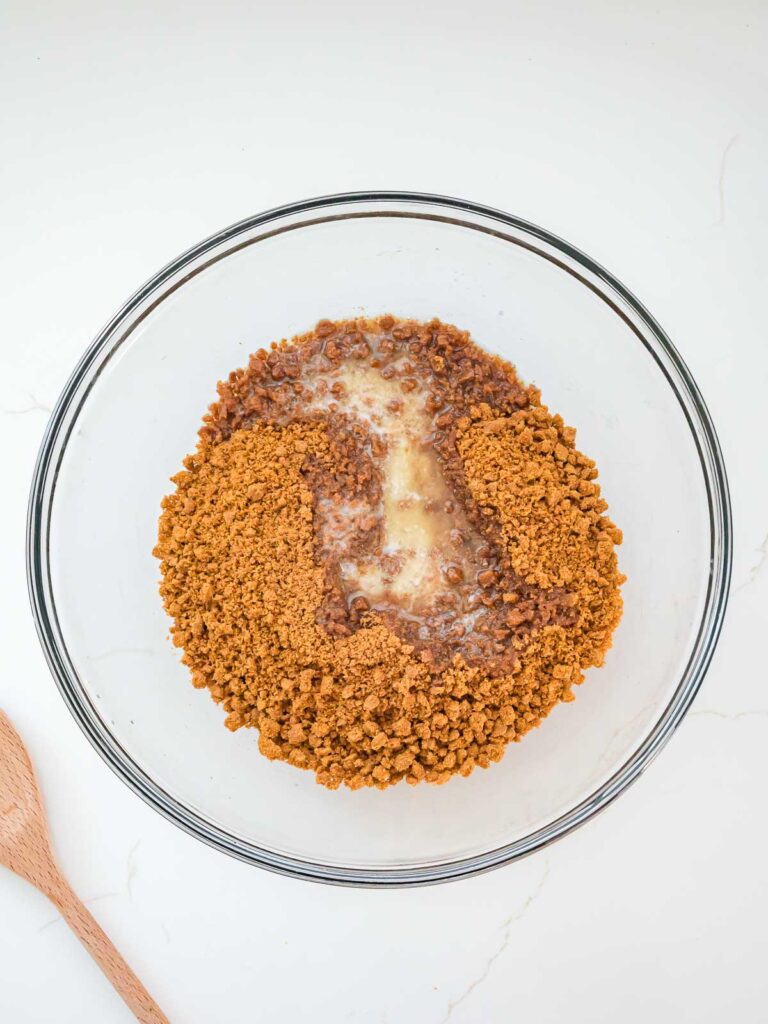 Crushed Biscoff cookies and melted butter mixed in a glass bowl to make the crust.