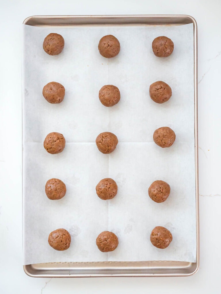 Rolled Biscoff truffle mixture shaped into balls and placed on a parchment-lined baking sheet before chilling.