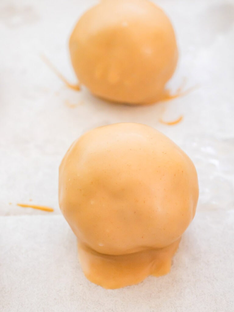 Freshly dipped Biscoff truffle coated in cookie butter and white chocolate setting on parchment paper.
