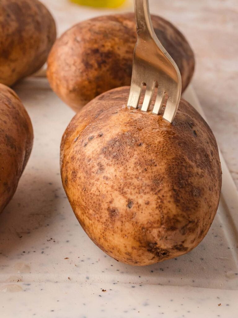 Pricking a russet potato with a fork before cooking.