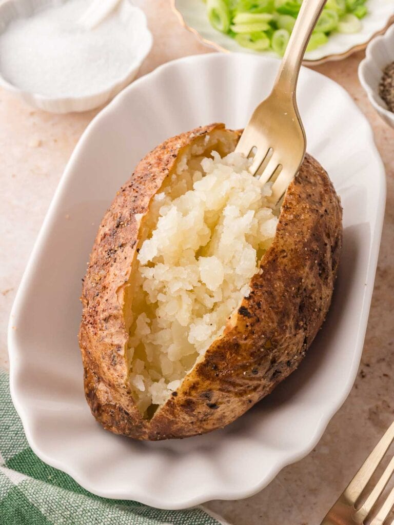 Fluffy inside of a baked potato being loosened with a fork.