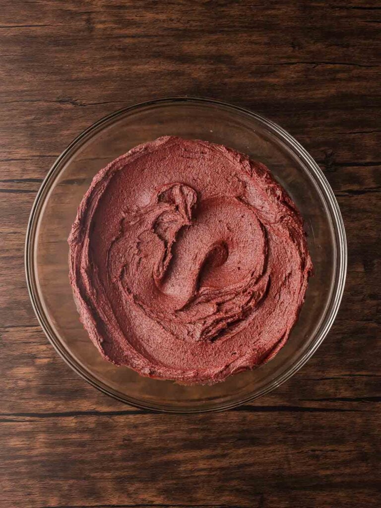 Smooth, vibrant red velvet crinkle cookie dough fully mixed and ready to chill before baking.
