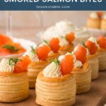 Row of smoked salmon vol au vents on a wooden board with more smoked salmon behind by Tessie's Table.