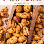 Wooden scoop full of spiced peanuts coated in chili powder and garlic by Tessie's Table.