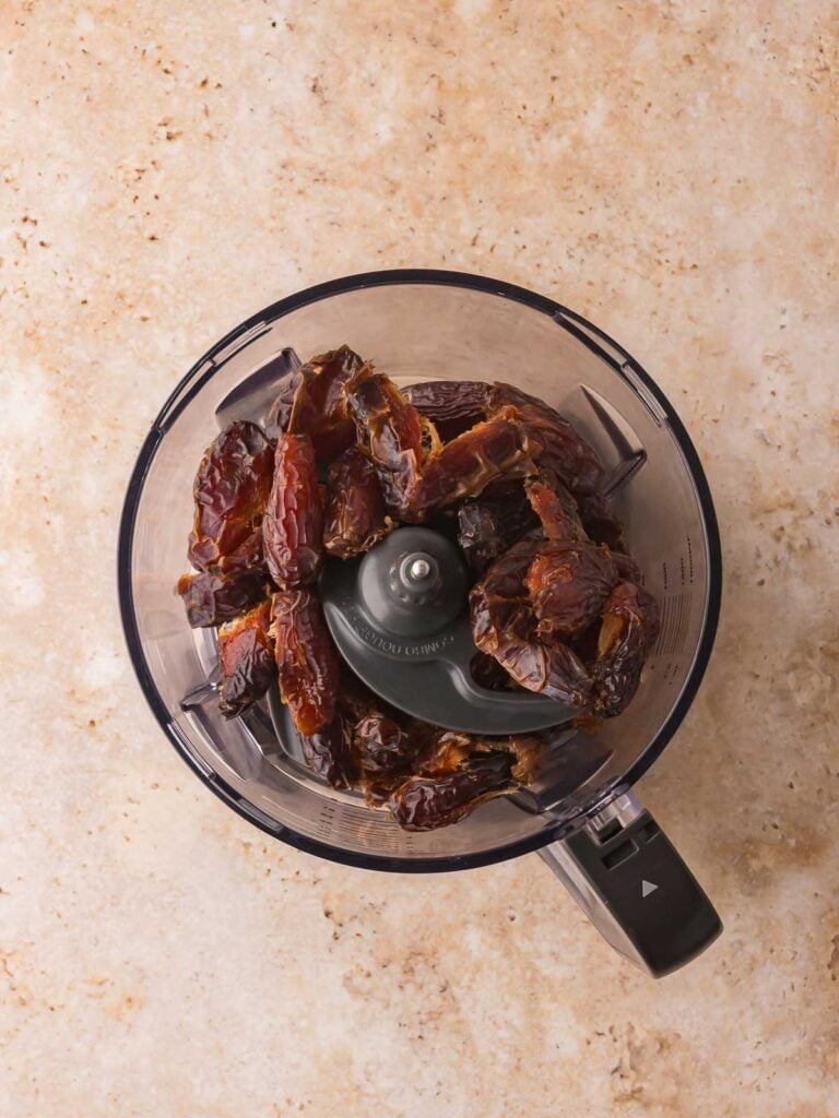 Medjool dates placed in a food processor to start the base for chocolate peanut butter protein bars.