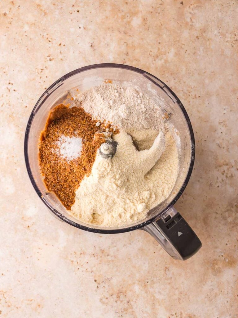 Oat flour, protein powder, flaxseed, vanilla, and salt added to the blended date mixture in a food processor.