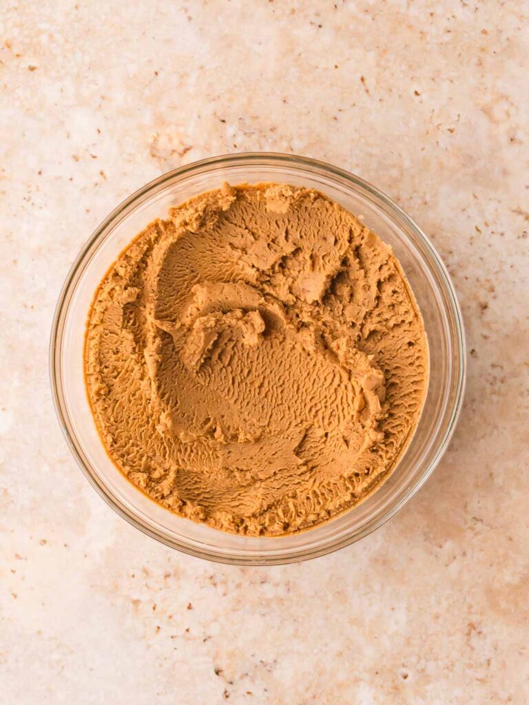 Bowl of PB2 mixed with water into a thick peanut butter paste for protein ball mixture.