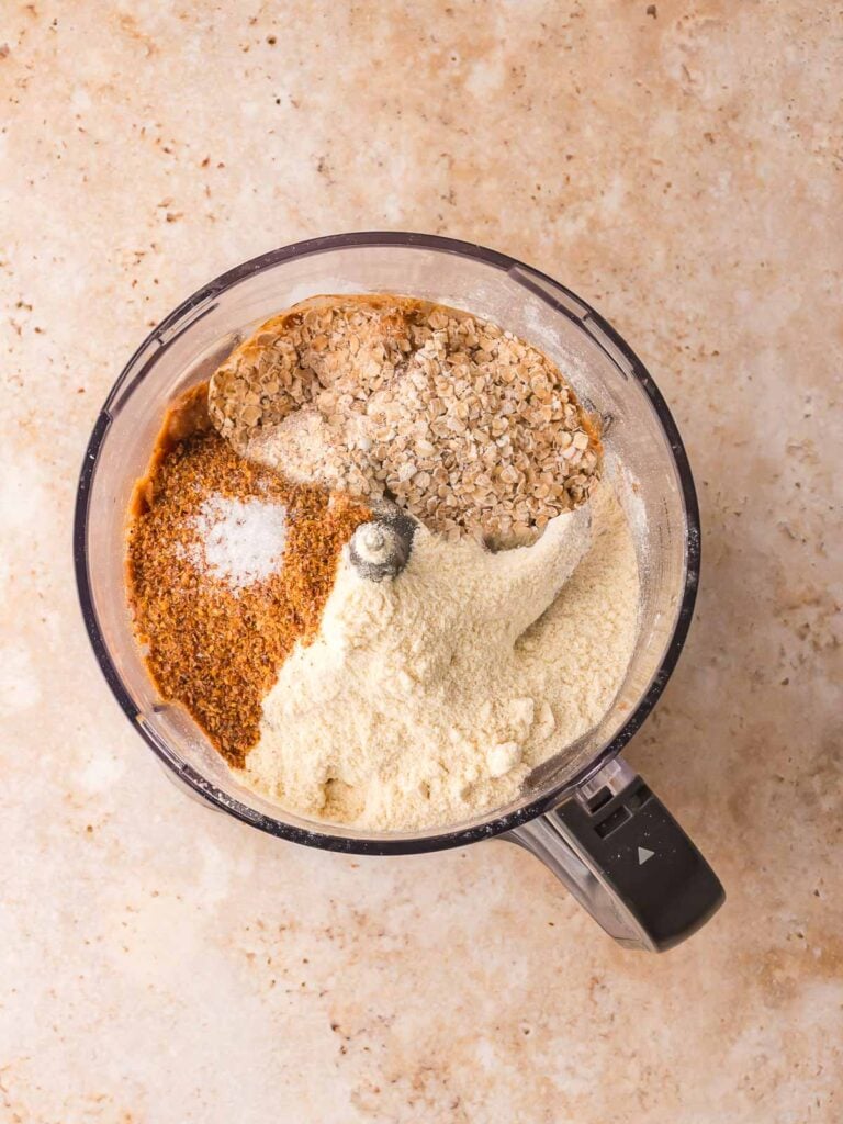 Quick oats, protein powder, flaxseed, vanilla, and salt added on top of the date mixture for peanut butter protein balls.