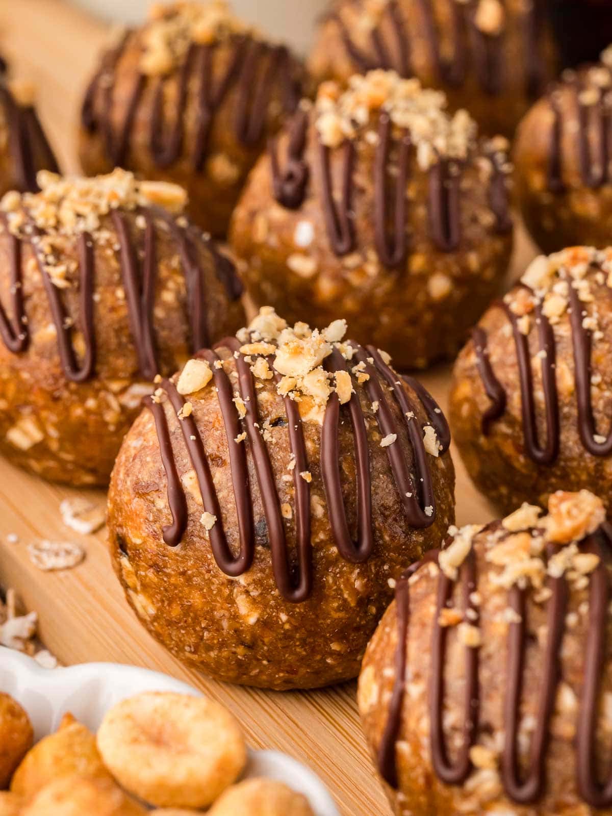 Rows of peanut butter protein balls drizzled with chocolate and sprinkled with crushed peanuts.