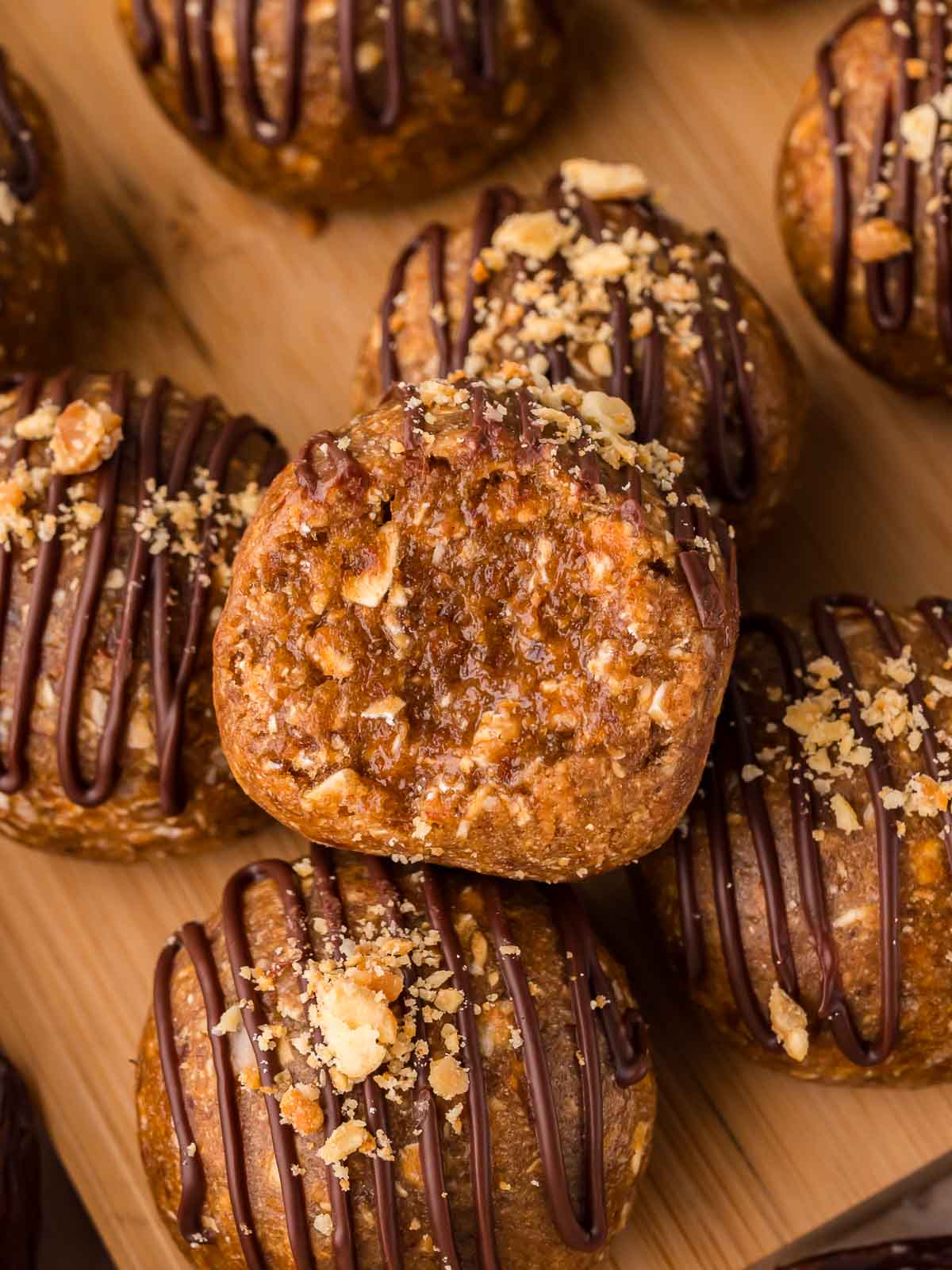 Close-up of a peanut butter protein ball topped with crushed peanuts and chocolate drizzle.