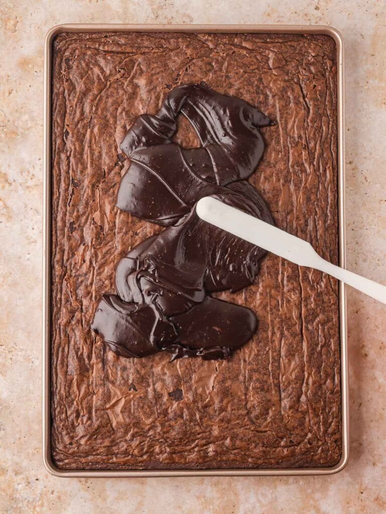 Warm frosting being poured over the warm cake.