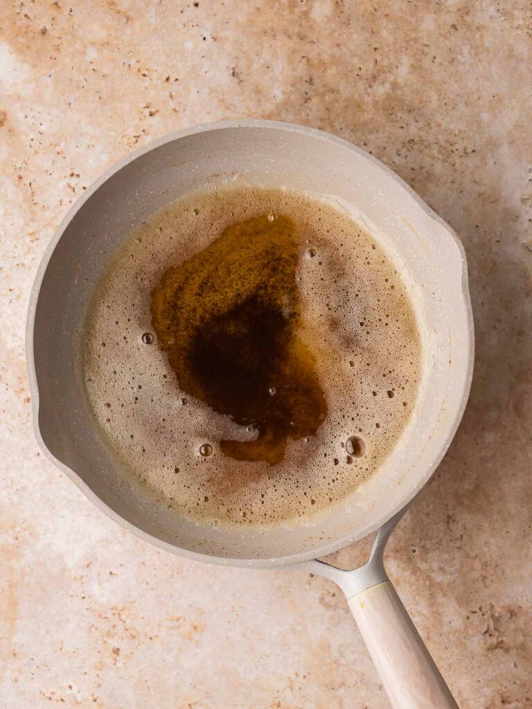 Brown butter melted in a saucepan, showing golden color and browned bits forming on the bottom.