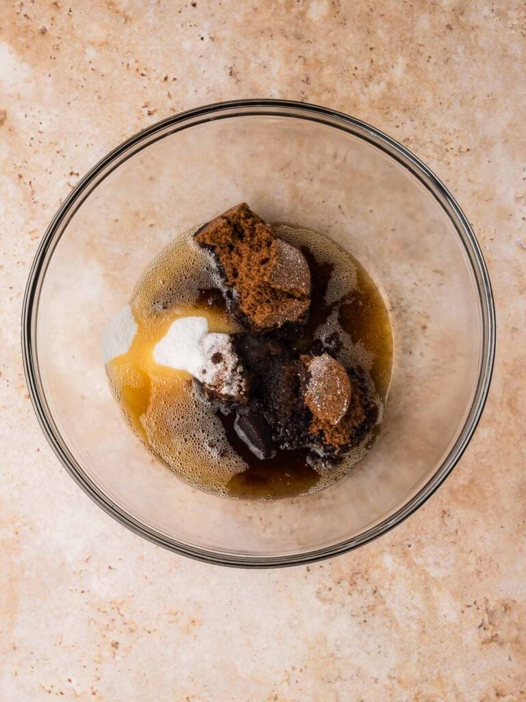 Brown butter added to a mixing bowl with brown sugar and granulated sugar before mixing.