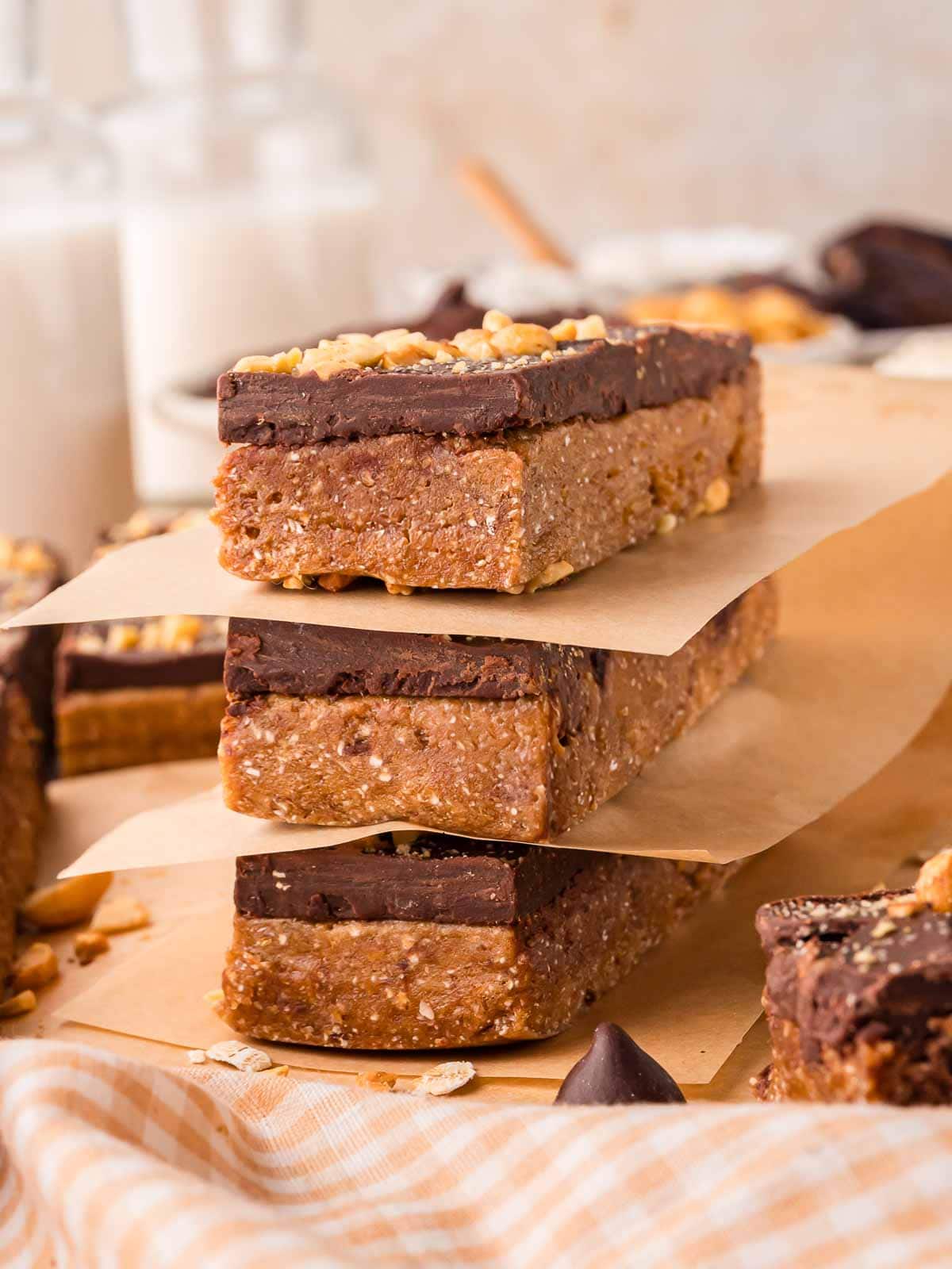 Three chocolate peanut butter protein bars stacked with parchment sheets between them for an easy grab-and-go snack.