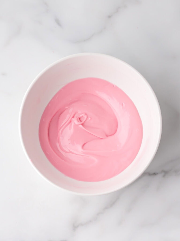 Smooth pink chocolate melts in a white bowl.