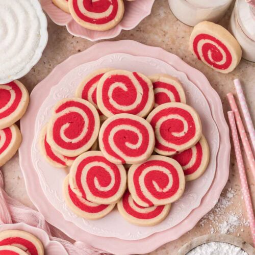 pinwheel cookies styled on a pink dessert table with milk and powdered sugar.