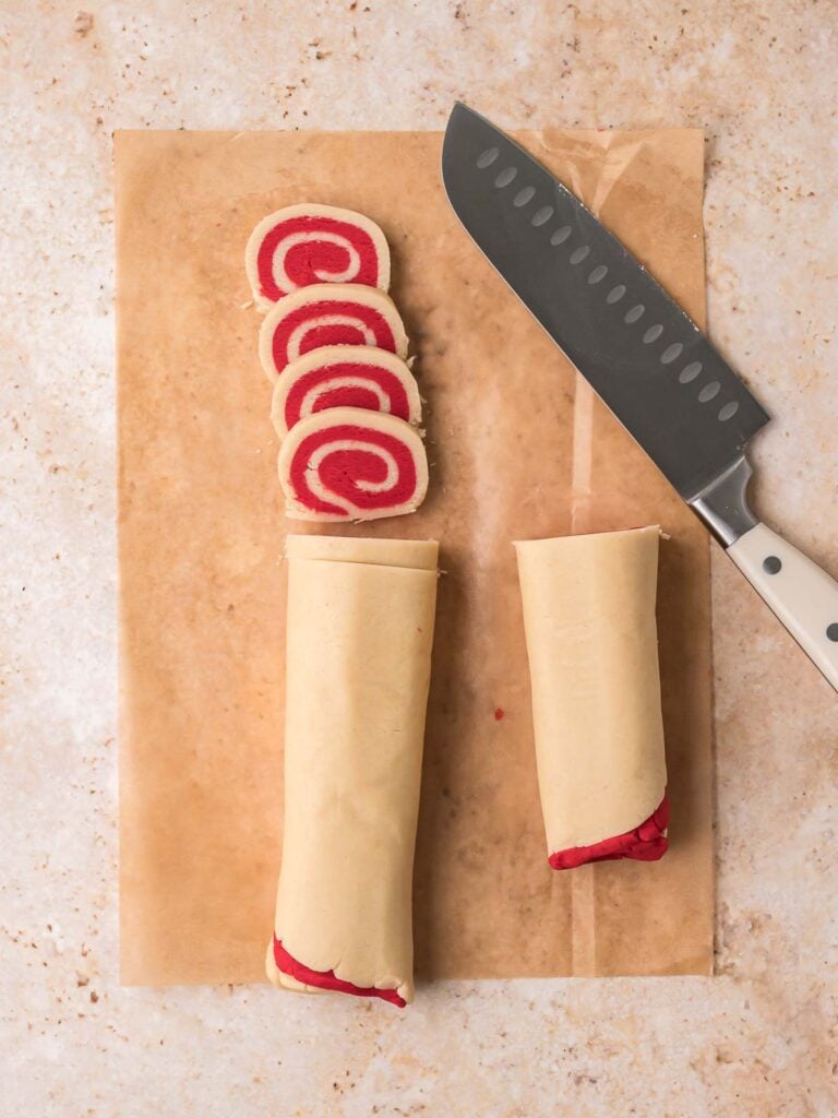 Pinwheel cookie dough rolled into logs and sliced with a sharp knife.