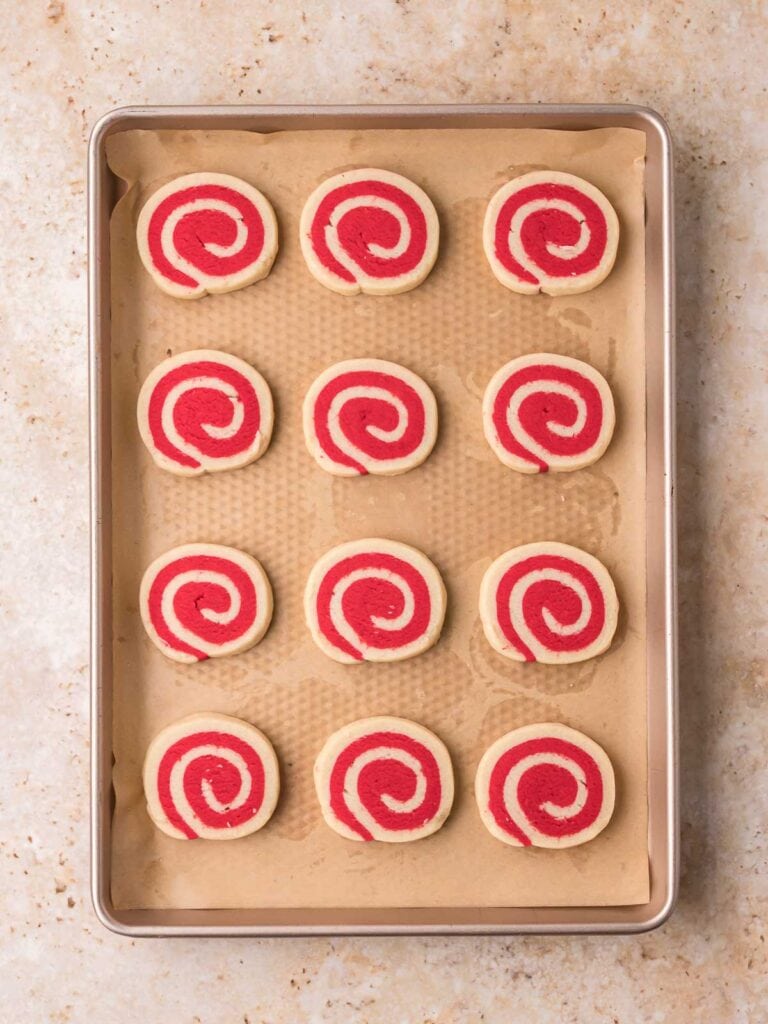 Baked pinwheel cookies arranged on a parchment-lined baking sheet