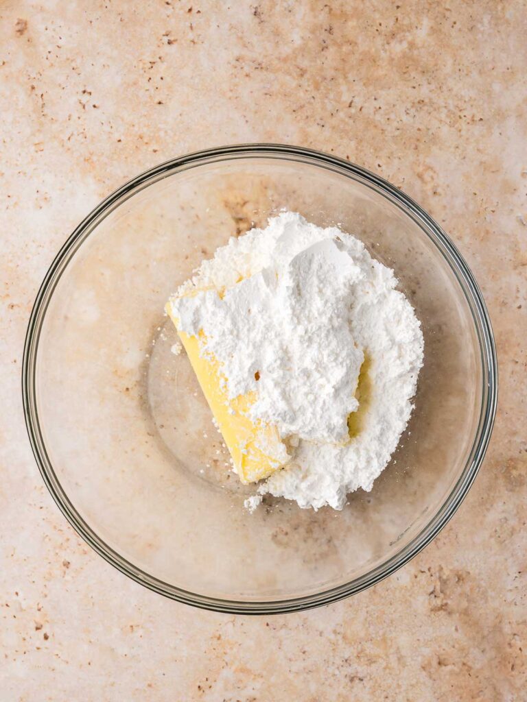 Softened butter and powdered sugar in a glass mixing bowl for pinwheel cookies.