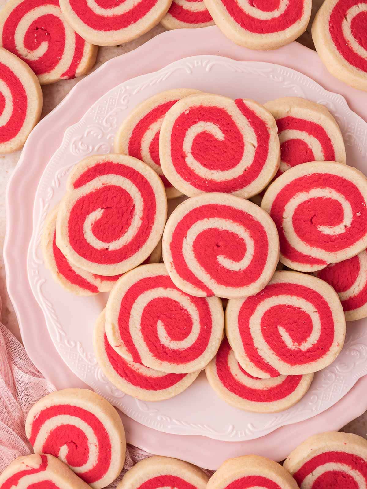 Plate of red and white pinwheel cookies displayed on a pink platter.