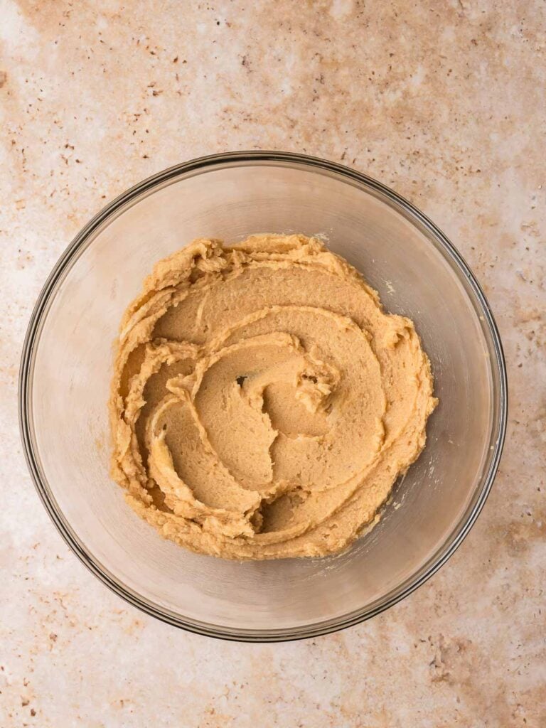 Creamed butter and sugar mixture in a glass mixing bowl for white chocolate cranberry cookies.