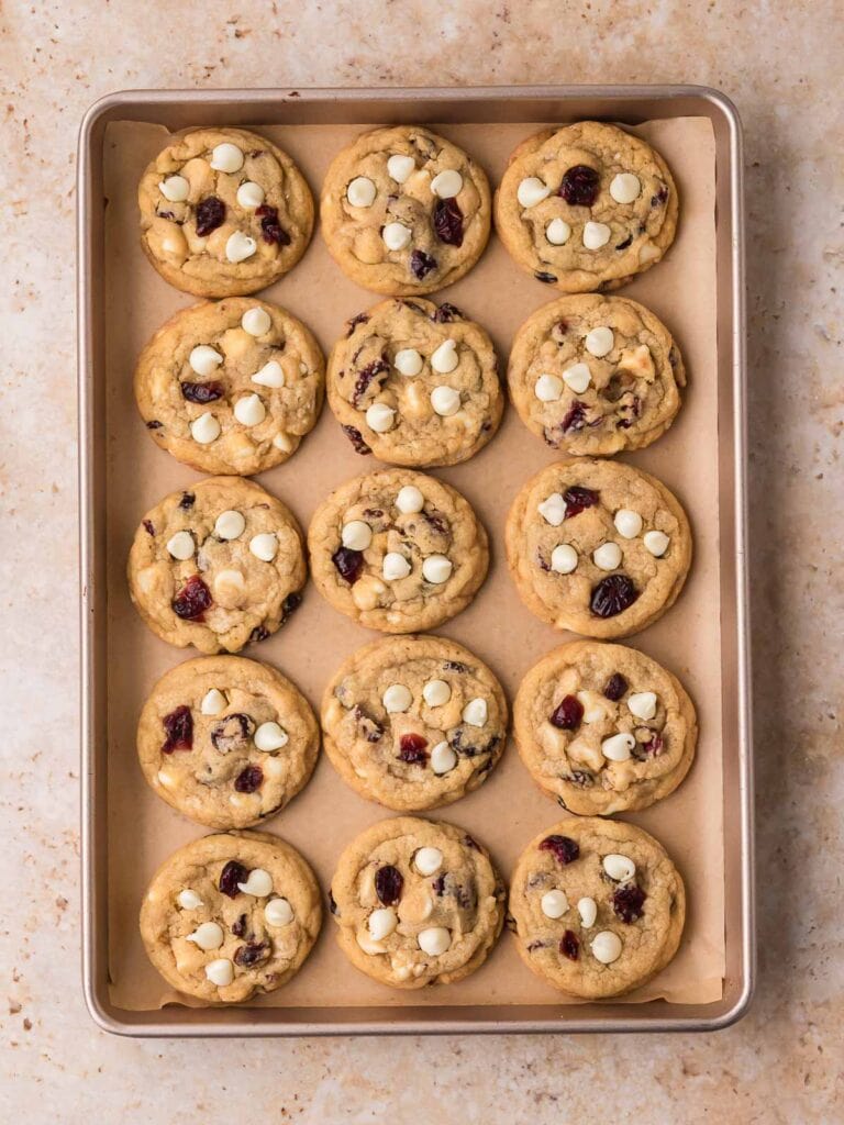Freshly baked white chocolate cranberry cookies on a baking sheet.