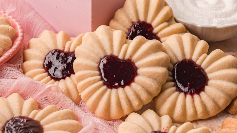 Heart jam cookies displayed together with a pink box and small bowl of jam nearby.