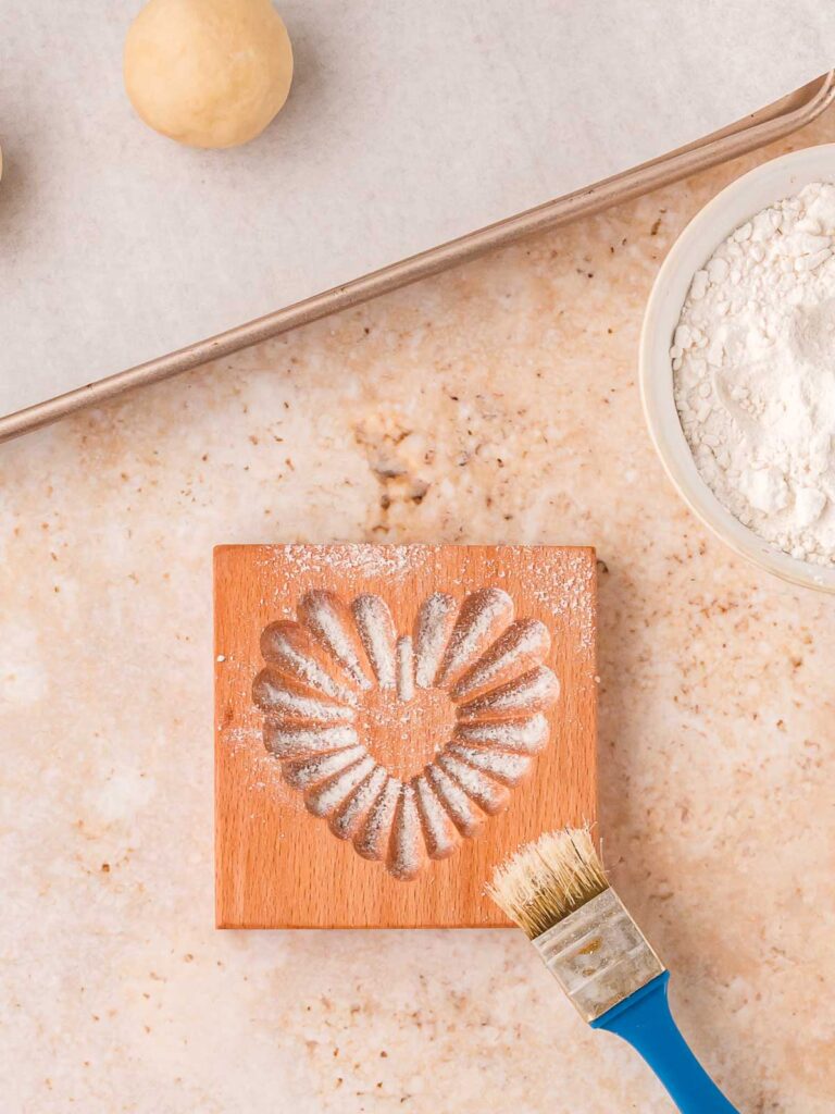 Wooden heart cookie stamp dusted generously with flour to prevent sticking.
