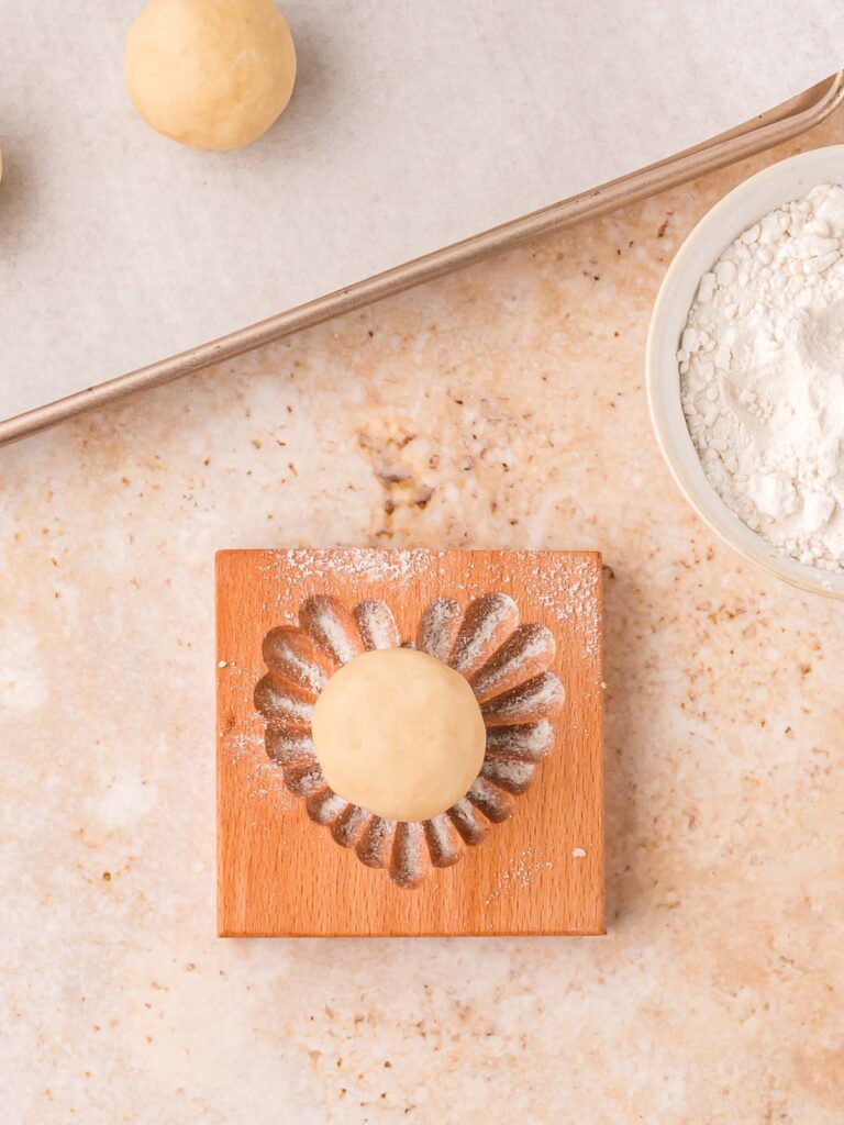 Dough ball placed into the floured wooden heart cookie stamp.
