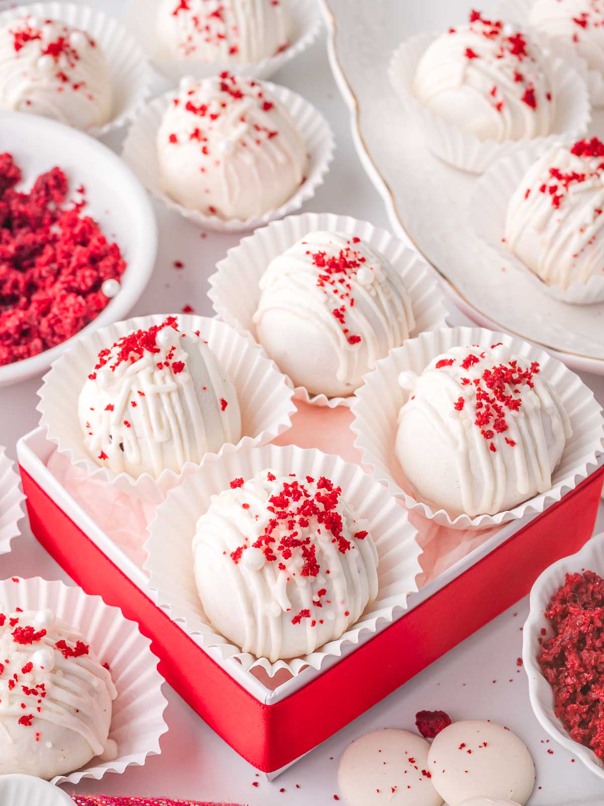 Red velvet truffles arranged in a red gift box with white liners and red velvet crumb topping.