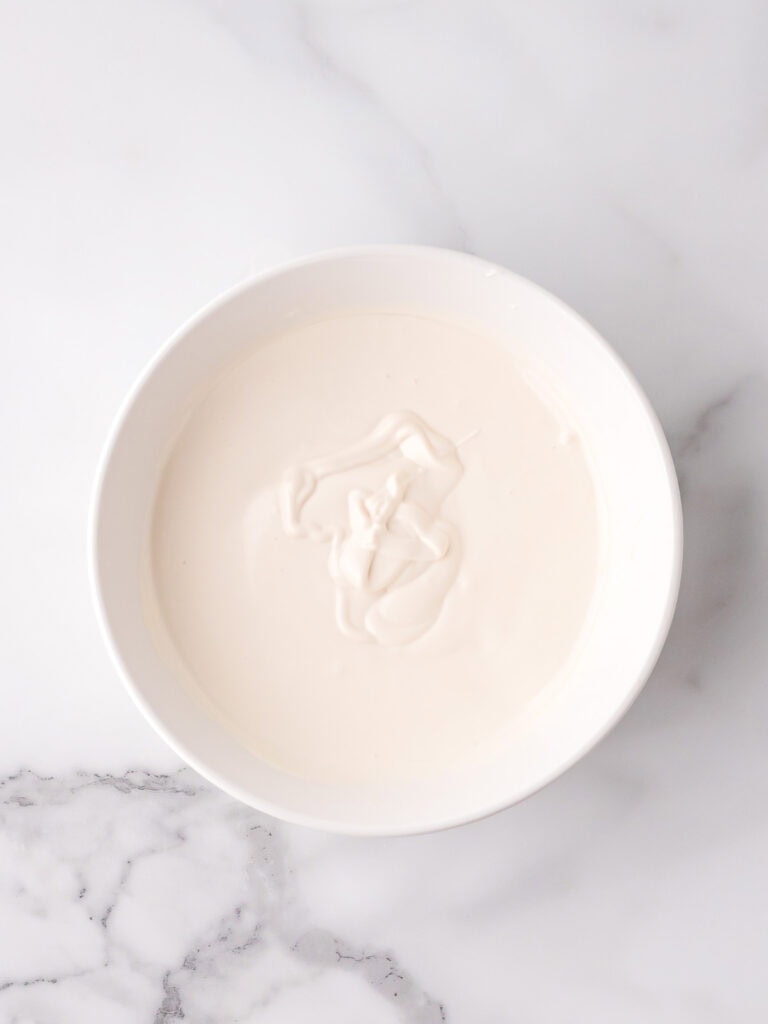 Melted white candy melts in a bowl ready for dipping red velvet truffles.