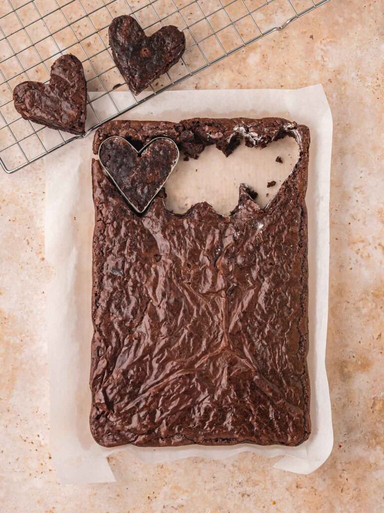 Heart-shaped brownies cut from a baked brownie slab using a heart cookie cutter.