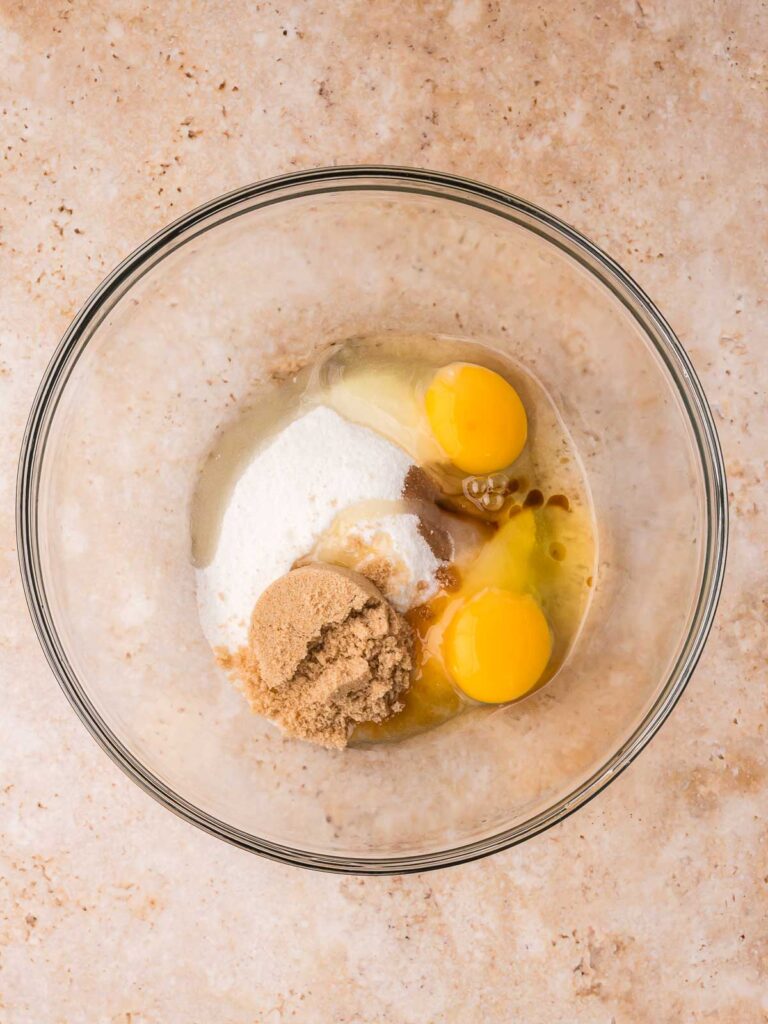 Eggs, sugar, and vanilla in a mixing bowl for making brownie cookie batter.