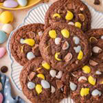 Plate of Cadbury Egg brownie cookies with chocolate chunks and colorful mini eggs.