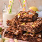 Cadbury egg brownies served on a plate with pastel Easter eggs and milk in the background.