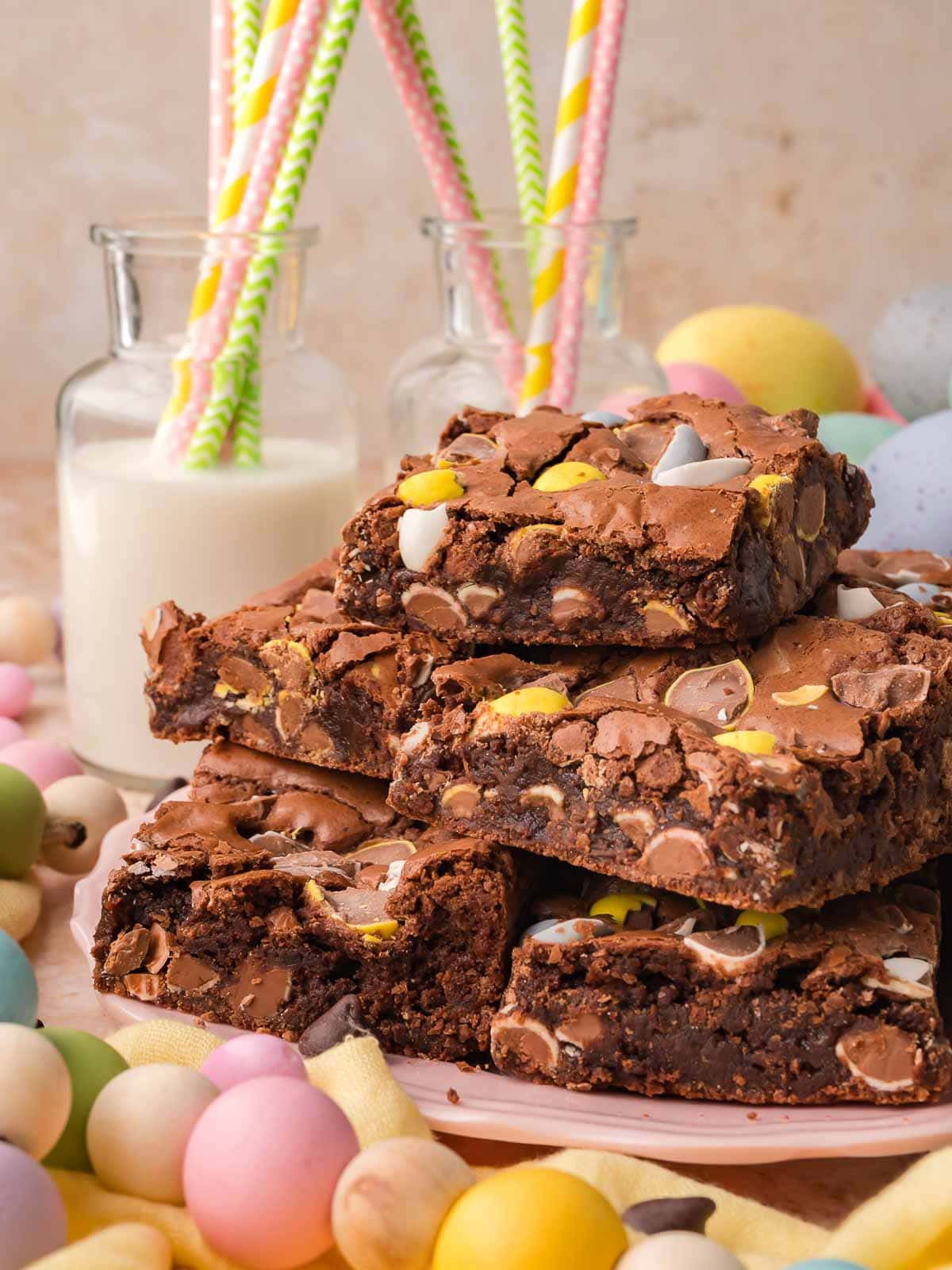 Cadbury egg brownies served on a plate with pastel Easter eggs and milk in the background.